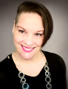 Photo of Jayde, a light skinned woman with short brown hair, magenta lipstick, a big smile and black shirt.